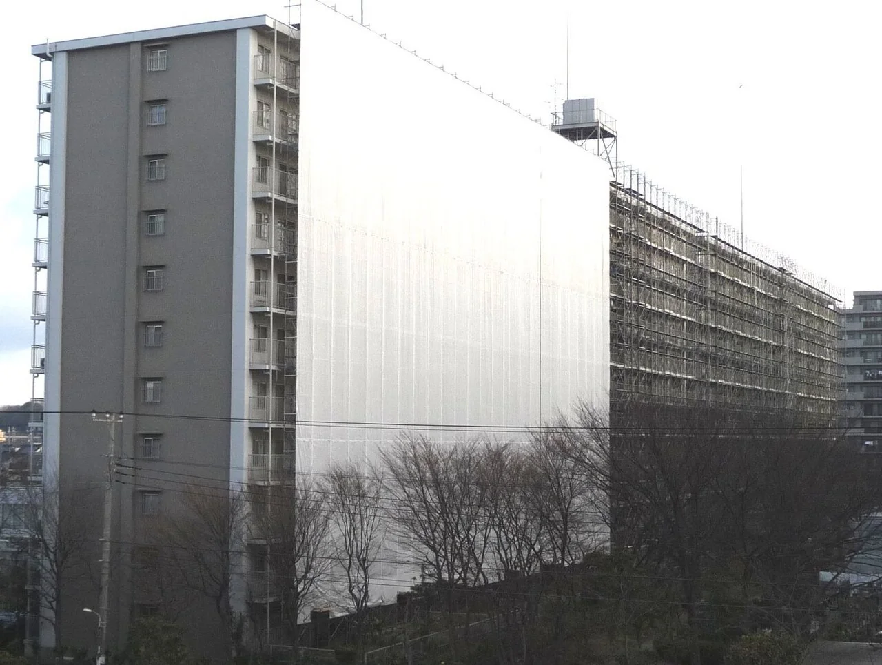 日本公寓整棟被鷹架與白色防護網包住，正在進行大規模修繕